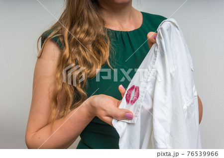 Woman holding a shirt with lipstick of her unfaithful husband Woman holding a shirt with lipstick of her unfaithful husband 76539966