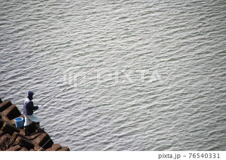 テトラから獲物を狙う釣り人 76540331