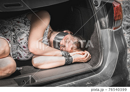 Woman with tied hands inside car trunk - kidnapping Woman with tied hands inside car trunk - kidnapping 76540399