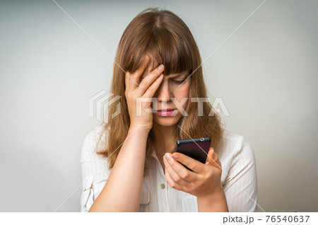 Disappointed woman holding and looking on mobile phone Disappointed woman holding and looking on mobile phone 76540637