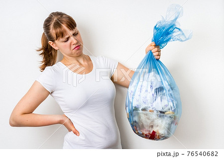 Woman holding a smelly garbage bag 76540682