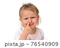 Sad baby girl is picking her nose with finger inside 76540909