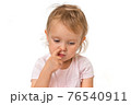 Baby girl is picking her nose with finger inside 76540911