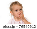 Baby girl is picking her nose with finger inside 76540912