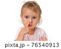 Baby girl is picking her nose with finger inside 76540913