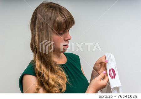 Woman holding a shirt with lipstick of her unfaithful husband Woman holding a shirt with lipstick of her unfaithful husband 76541028