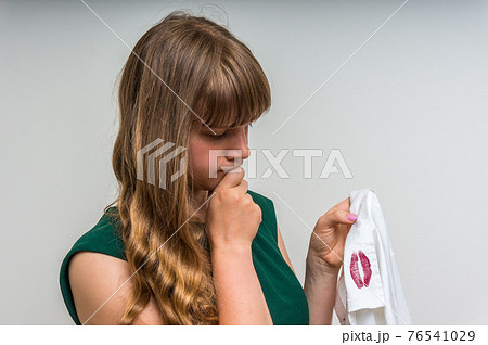 Woman holding a shirt with lipstick of her unfaithful husband 76541029
