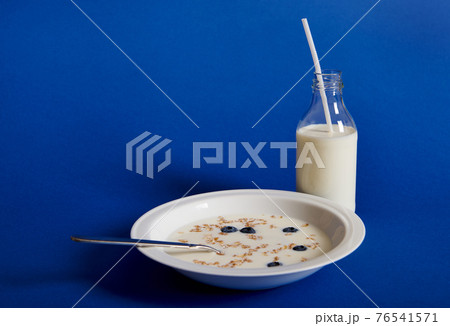 Closeup composition of fresh milk and a plate of muesli with berries, isolated on blue background 76541571