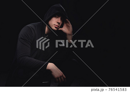 Studio portrait of a man in a hood, a shadow hides his face. Anonymity shadow economy and evasion from the law 76541583