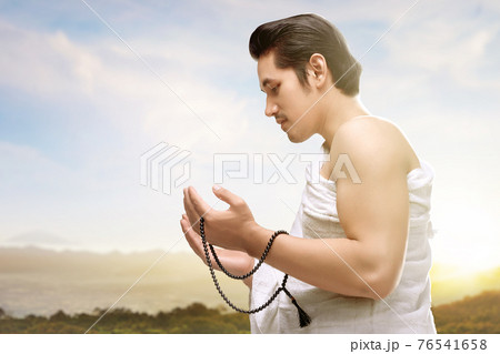 Asian Muslim man in ihram clothes praying with prayer beads on his hands 76541658