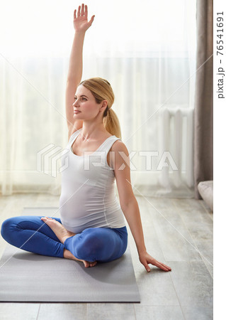 healthy pregnant woman sit on floor raising hands up, exercising 76541691