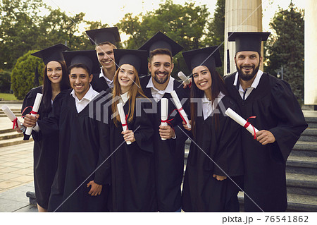 Group of happy graduates walking with dimplomas in raised hands over university building background Group of happy graduates walking with dimplomas in raised hands over university building background 76541862