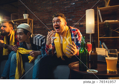 Group of friends watching TV, sport match together. Emotional fans cheering for favourite team, watching on exciting game. Concept of friendship, leisure activity, emotions 76541957