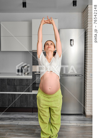 pregnant female with naked big tummy practice yoga exercises, standing stretching arms up pregnant female with naked big tummy practice yoga exercises, standing stretching arms up 76542148