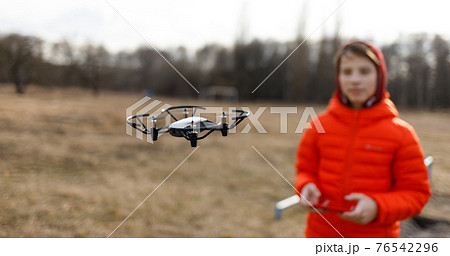 Teenage boy flying small drone in the park 76542296