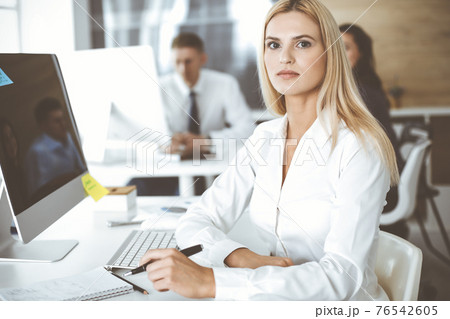Business woman using computer at workplace in modern office. Secretary or female lawyer smiling and looks happy. Working for pleasure and success Business woman using computer at workplace in modern office. Secretary or female lawyer smiling and looks happy. Working for pleasure and success 76542605