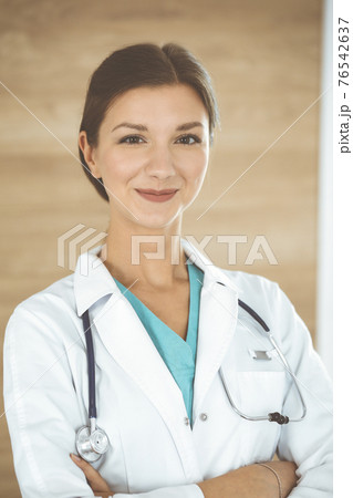 Doctor woman standing and looking at camera. Physician at work, studio portrait at medical background. Medicine and health care concept 76542637