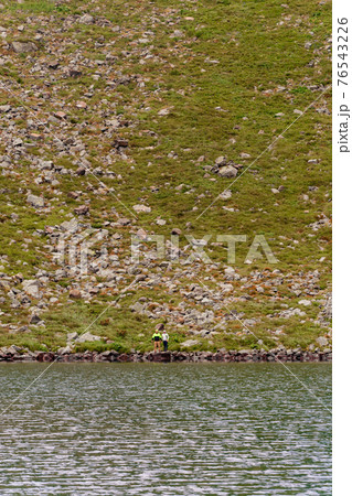 A couple of tourists stand on the edge of a mountain lake, Lake Brebeneskul, the Montenegrin ridge, the Carpathians of Ukraine. 76543226