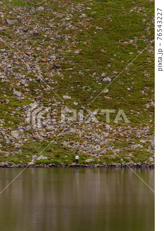Alpine lake Brebeneskul, the cradle of the Carpathians, a couple of tourists near the lake, reflection in the water. 76543227