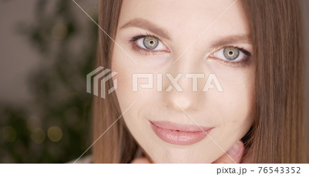 Beauty woman face with green eyes looking at camera. Skin care treatment or cosmetic ads concept. Beautiful female model with perfect fresh and clean skin. Nude make-up. In studio. 76543352