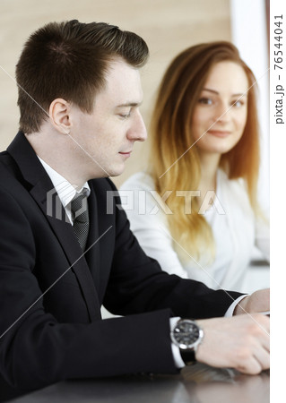 Business people or lawyers discussing questions at meeting in sunny office. Unknown businessman and woman with colleague sitting and working at the glass desk Business people or lawyers discussing questions at meeting in sunny office. Unknown businessman and woman with colleague sitting and working at the glass desk 76544041