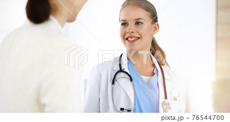 Woman - doctor consults her female patient in sunny clinic 76544700