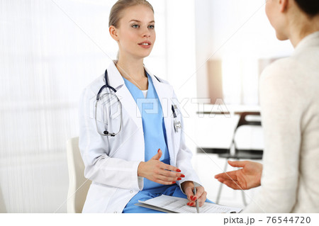 Woman - doctor consults her female patient in sunny clinic 76544720