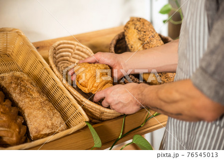Hands of man stacking bakery products in baskets 76545013