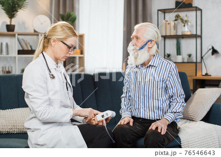 Asthma treatment for elderly geriatric patients. Caucasian woman doctor general practitioner helping her senior man patient to make inhalation with nebulizer, during home visit Asthma treatment for elderly geriatric patients. Caucasian woman doctor general practitioner helping her senior man patient to make inhalation with nebulizer, during home visit 76546643