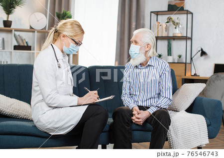 Mature woman doctor filling checkup form during home visit of retired bearded man patient, writing in documents, medical history or anamnesis, medical insurance contract 76546743