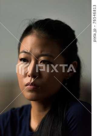 Close-up portrait of beautiful rebel Asian woman face looking sad and serious outdoors 76546813