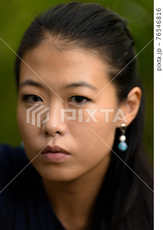 Close-up portrait of beautiful rebel Asian woman face outdoors 76546816