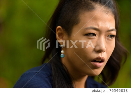 Close-up portrait of beautiful rebel Asian woman face outdoors 76546838