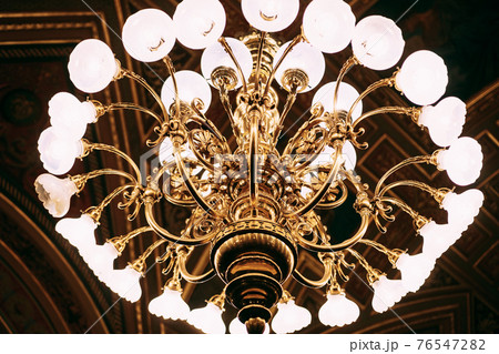 Close-up of a golden chandelier in the dark. Close-up of a golden chandelier in the dark. 76547282