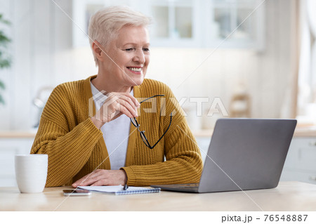 Senior woman looking at laptop screen and smiling 76548887
