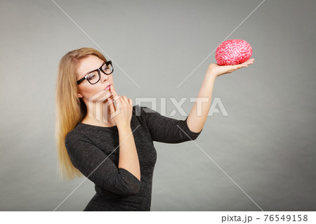 Woman thinking and holding fake brain 76549158