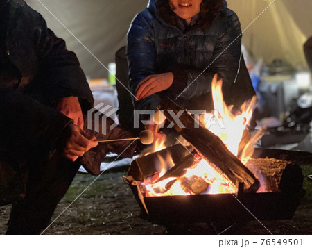 焚き火でマシュマロを焼く男女 76549501