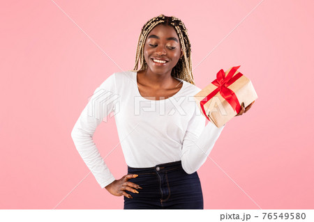 Happy black woman holding present box and thinking 76549580