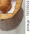 Sunny Breadbasket with long shadow on white wooden table top view. Closeup Bun in basket modern banner for snack food decorative design with copy space. Bright Corner bakery flat lay vertical concept 76550016