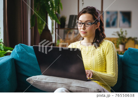 Businesswoman typing an e-mail on laptop at home office. 76550638