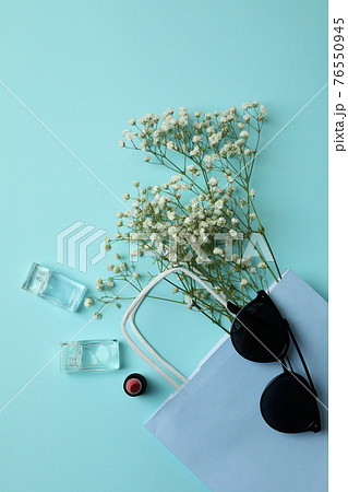 Bag, sunglasses, perfumes, lipstick and flowers on blue background 76550945