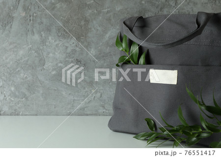 Stylish eco bag with branches against gray textured background Stylish eco bag with branches against gray textured background 76551417