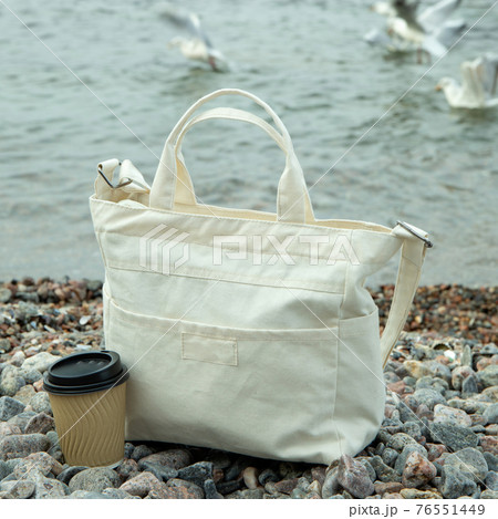 Stylish eco bag and paper cup outdoor on sea shore Stylish eco bag and paper cup outdoor on sea shore 76551449