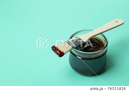 Glass jar of barbecue sauce and brush on mint background Glass jar of barbecue sauce and brush on mint background 76551826