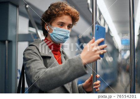 young woman using smartphone during subway ride. 76554201