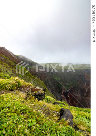 東京都大島町の伊豆大島にある火山三原山お鉢周りで見た雲や霧に覆われた噴火口 76556070