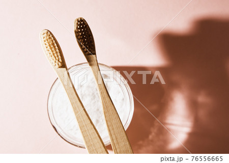 Two bamboo toothbrushes and tooth powder on pink background Two bamboo toothbrushes and tooth powder on pink background 76556665
