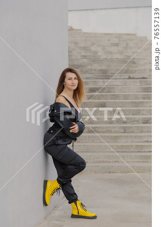 Beautiful young woman stands by the concrete Beautiful young woman stands by the concrete 76557139