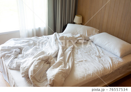 Messy bed. Couple pillows with white blanket on unmade bed. Messy bed. Couple pillows with white blanket on unmade bed. 76557534