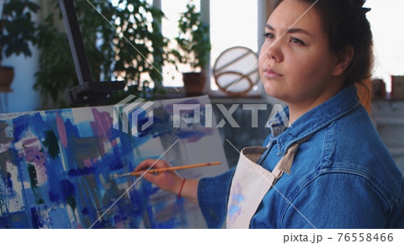 A woman artist drawing a painting and looking to the side 76558466